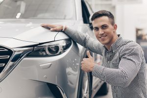 Junger Mann posiert vor einem Auto. Copywriting Marketing